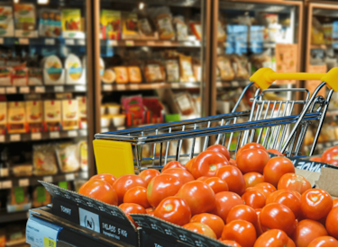 Matvaror i en livsmedelsbutik. Längst fram visas en stor mängd tomater.