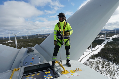 Besiktningsingenjör står längst upp på ett vindkraftverk.
