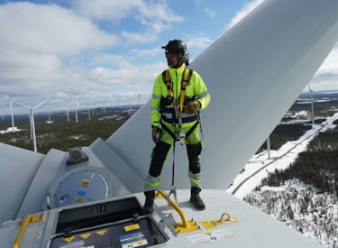 Besiktningsingenjör står längst upp på ett vindkraftverk.