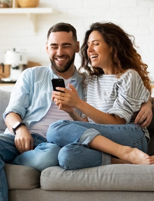 Man and woman sitting together on the couch looking at a phone