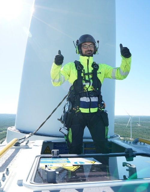 Kiwa inspector performing wind turbine inspecton giving two thumbs up while standing on the wind turbine
