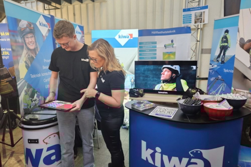 Två Kiwamedarbetare, man och kvinna, tittar på en tabletskärm i utställarmontern på Luleå arbetsmarknadsvecka (LARV).