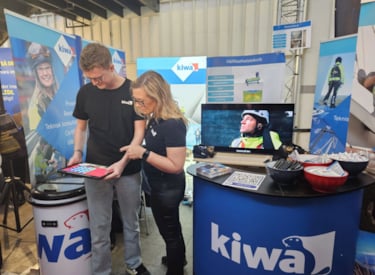 Två Kiwamedarbetare, man och kvinna, tittar på en tabletskärm i utställarmontern på Luleå arbetsmarknadsvecka (LARV).