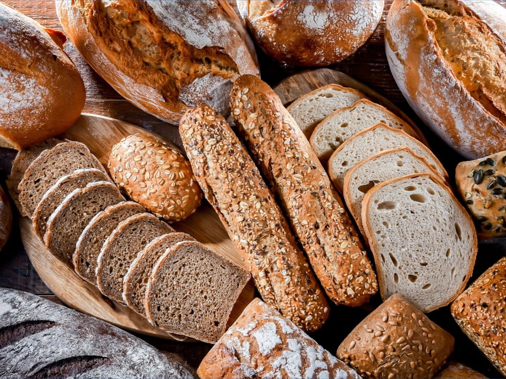 Different kinds freshly baked bread displayed on a table