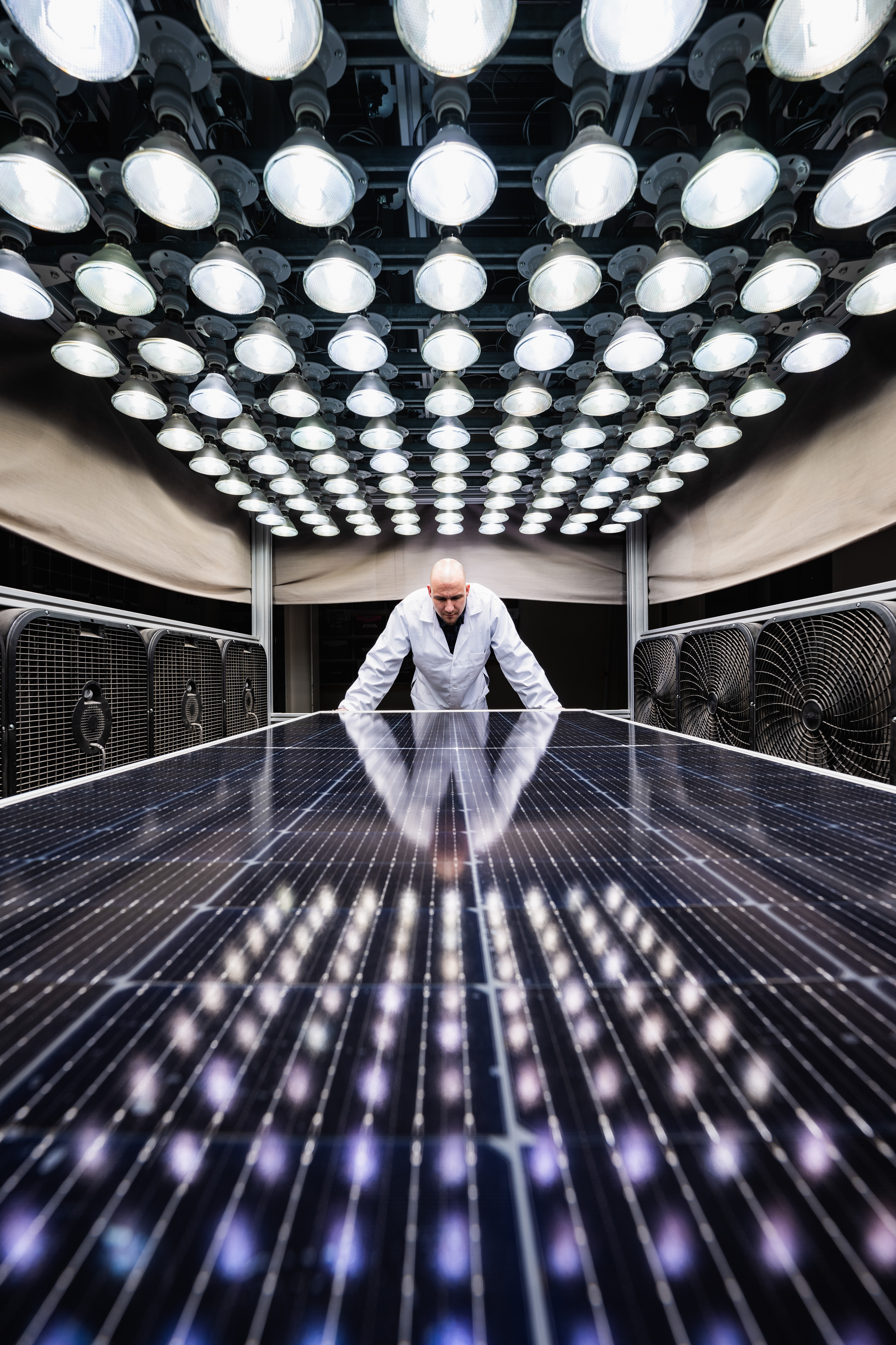 Kiwa lab employee examining solar panel under bright laboratory lights for renewable energy research