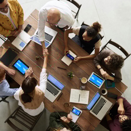 People sitting in an office working on their laptops, shaking hands
