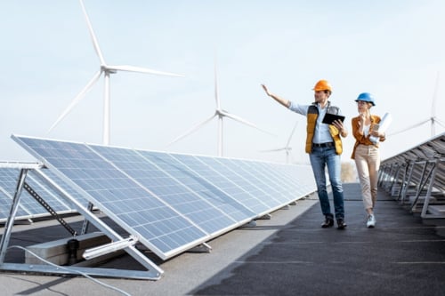 two enginers walk down a corridor of solar panels