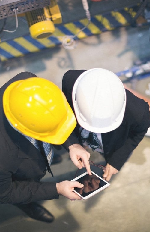 Två inspektörer, med varsin bygghjälm i olika färger, sedda ovanifrån