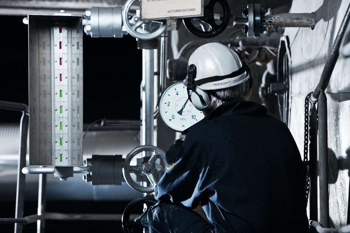 En person hanterar en tryckanläggning på en industri.  