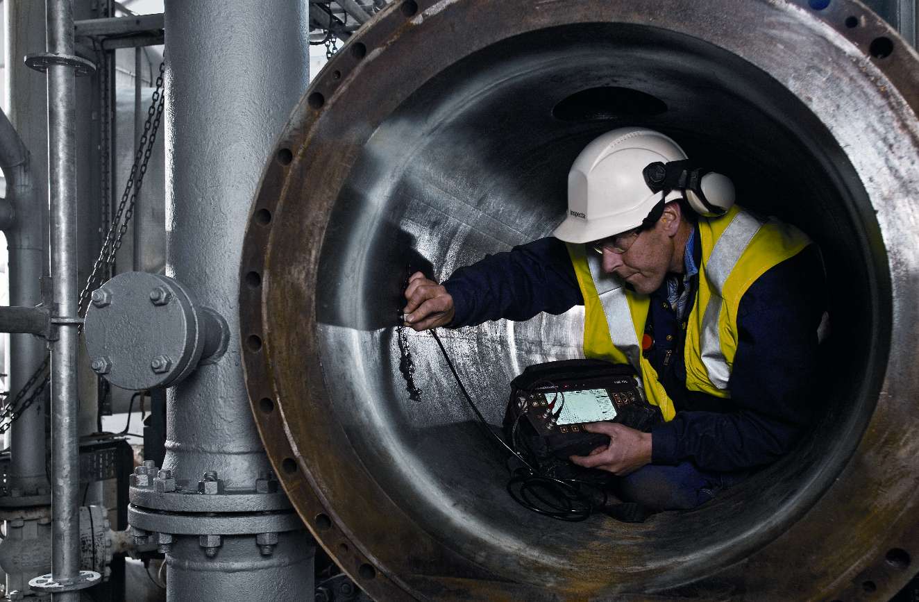 Besiktningsingenjör utför oförstörande provning i ett stort stålrör/ståltrumma för att kontrollera att inga sprickor uppstått. .  