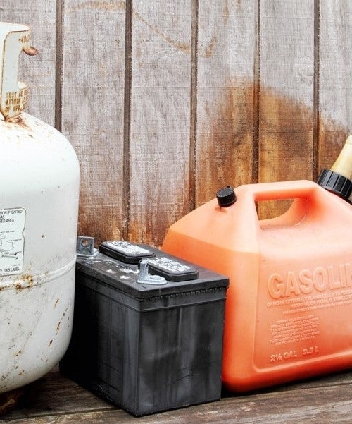 Behållare för kemikalier av olika slag: gasbehållare, bilbatteri, bensindunk och plastdunk för annan vätska.