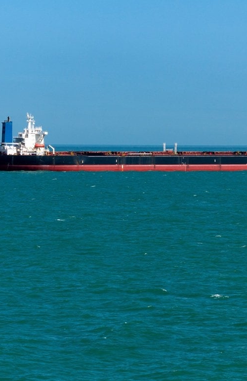 Stort lastfartyg på havet, med ett liknande fartyg längre bort, strax bakom, mot horisonten.