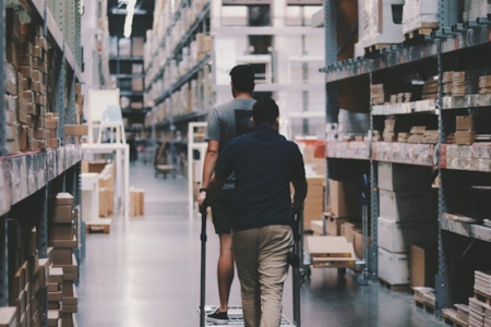 Två personer går runt i ett stort lager.