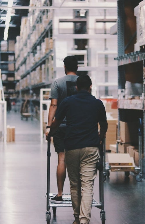 Två personer går runt i ett stort lager.