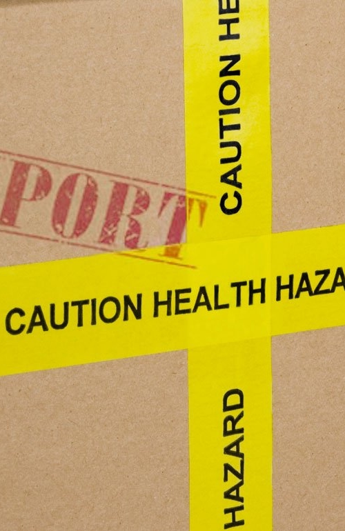 En förpackning i kartong, med fokus på en gul tejp med varningstext.