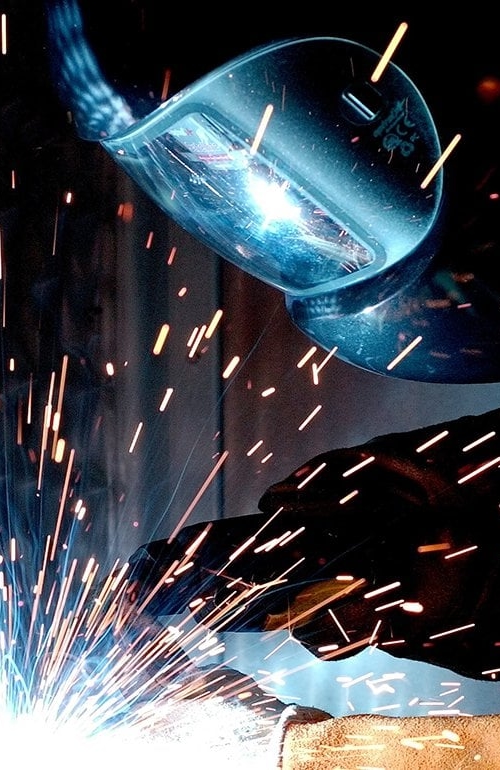 En svetsare med svetsmask arbetar.