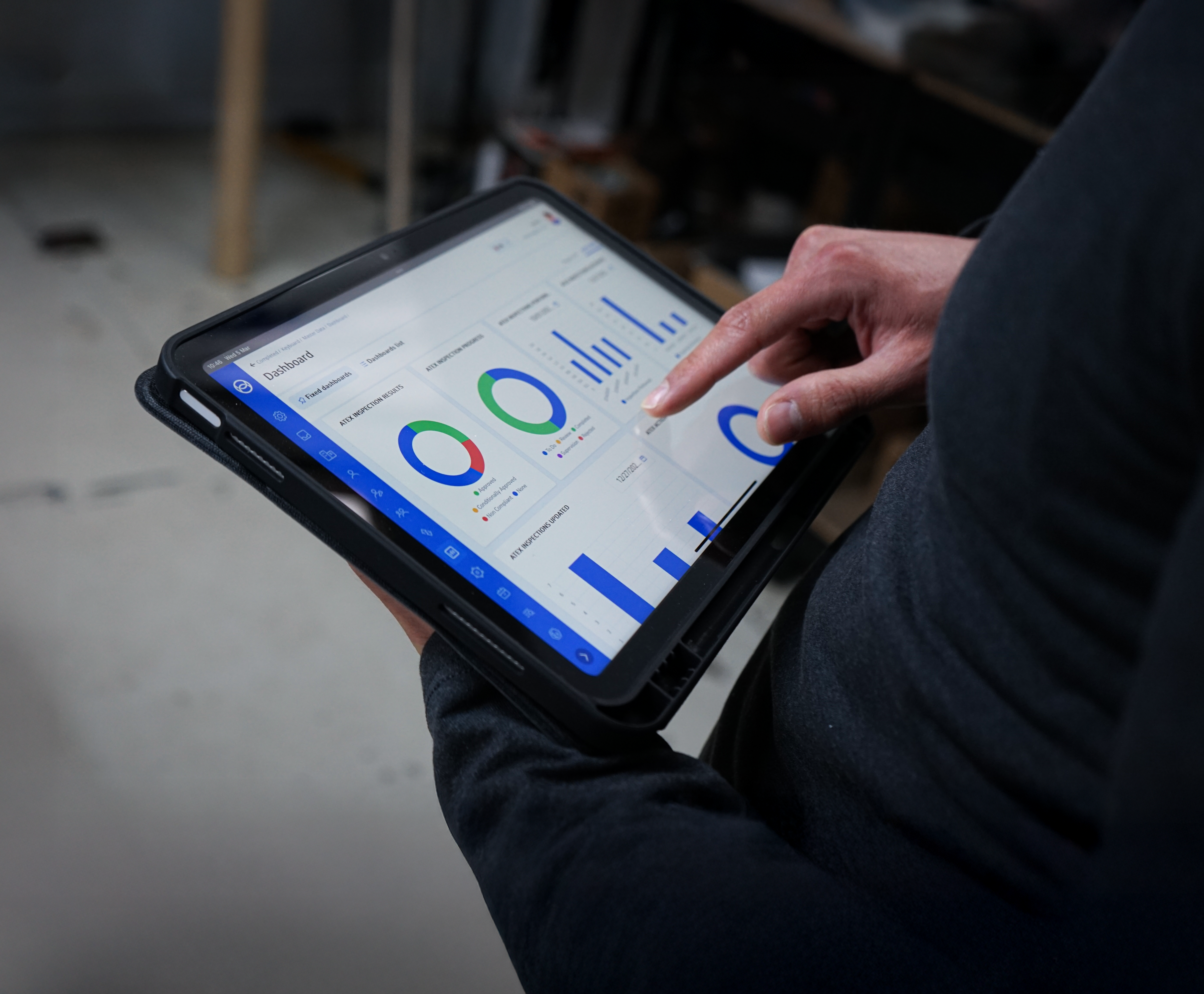Person using a tablet to view analytics dashboard with charts and graphs in a business setting