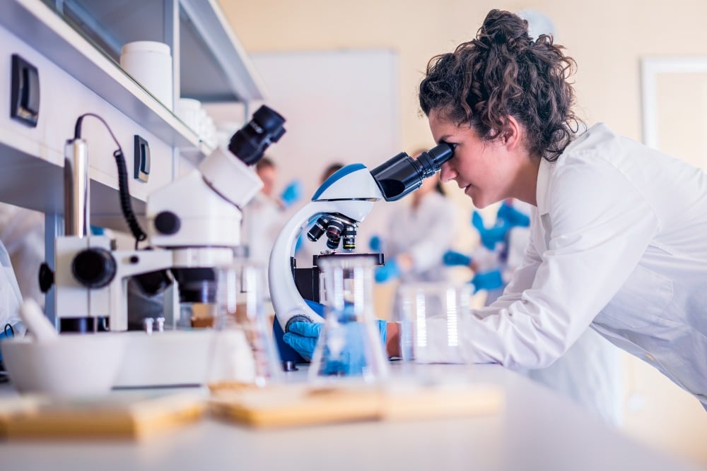 Female Kiwa laboratory employee looking in a microscope in a Kiwa laboratory