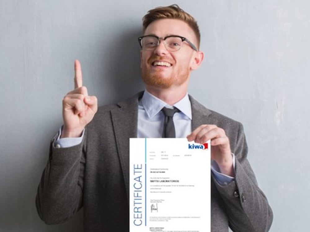 Kiwa employee dressed up in a suite holding a Kiwa certificate