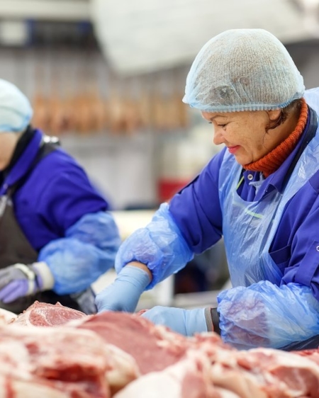 Two ladies working in meat production, sorting GLOBALG.A.P. certified meat