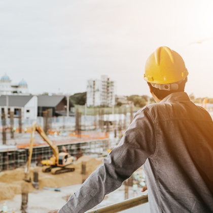Man met helm die uitkijkt over de bouwplaats