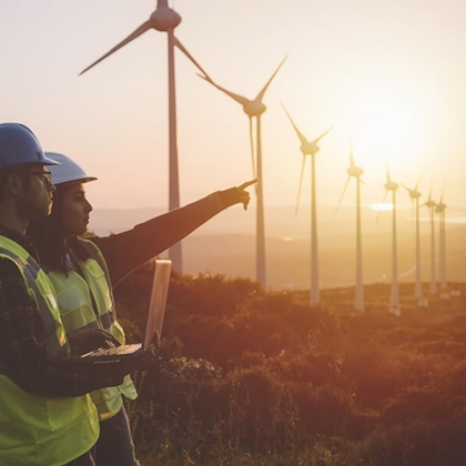 Two workers standing and pointing on a windmill field