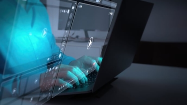 I skärmarna speglas en persons händer som skriver på ett tangentbord.