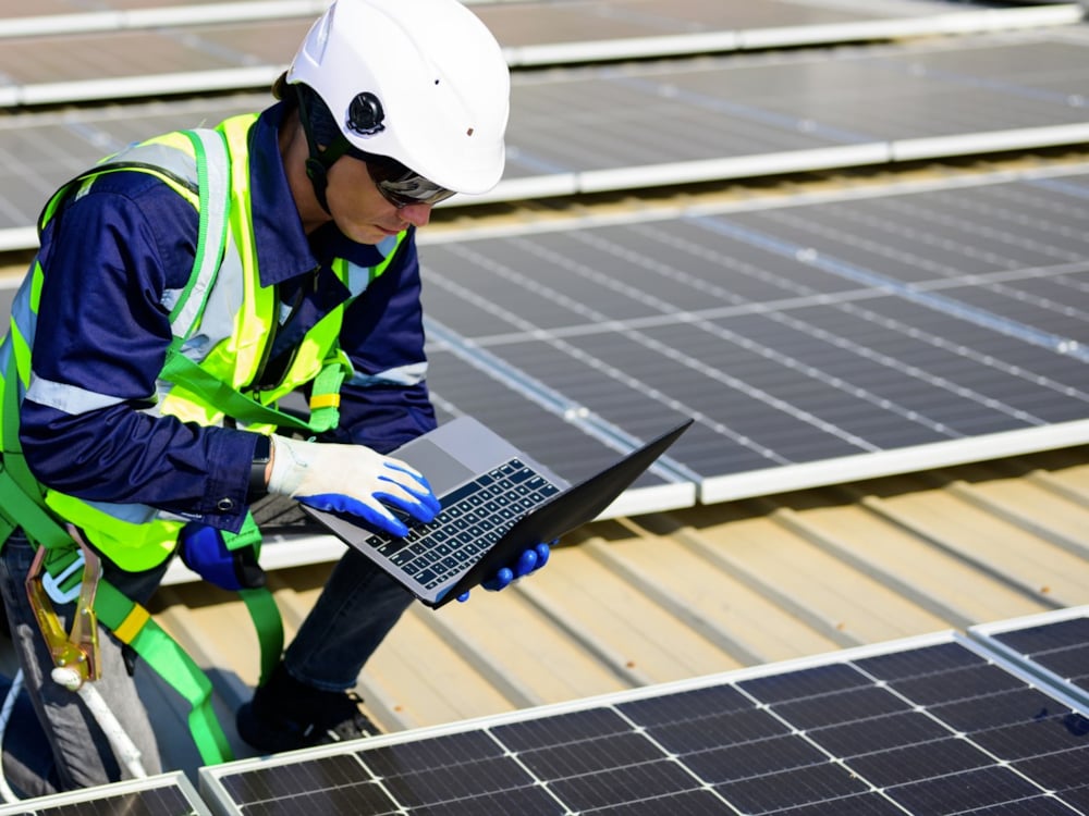 Kiwa PI Berlin inspector kneeling in front of a solar panel for inspection