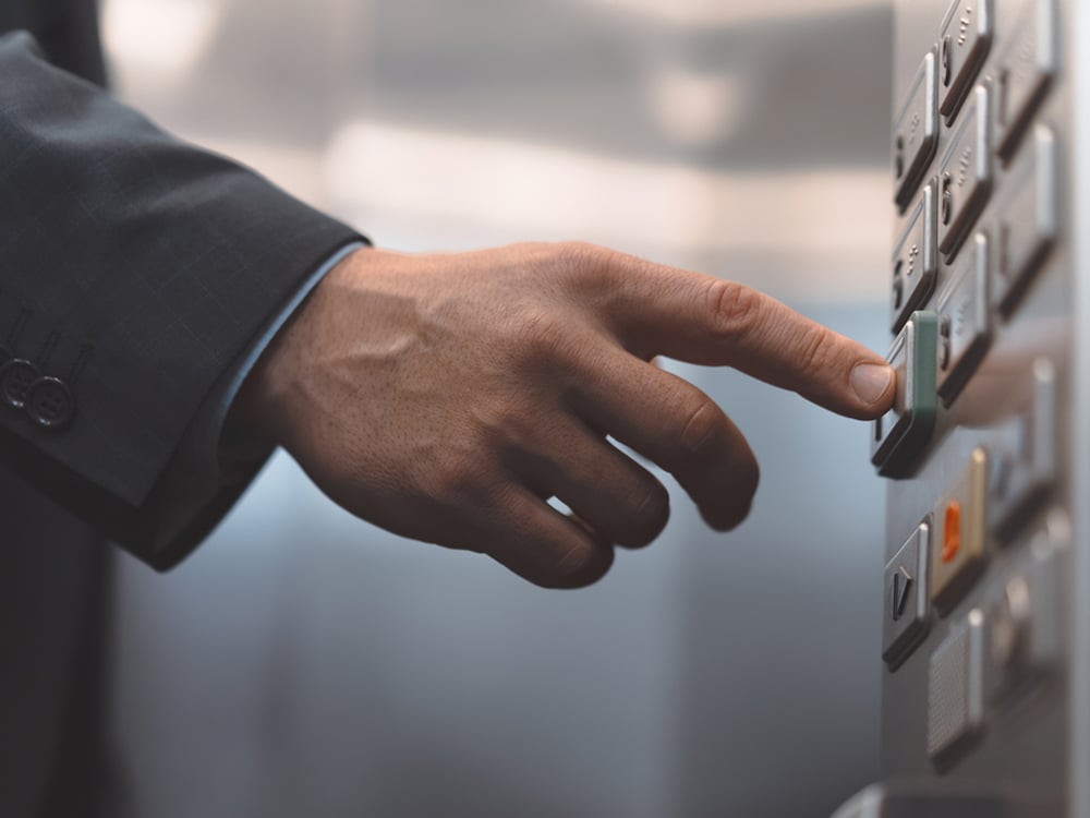 En person trycker på hissknappar.