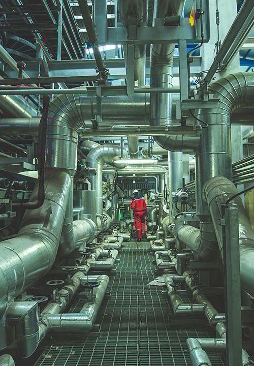 Industri där det visas många olika rörledningar kors och tvärs samt flera skorstenar.