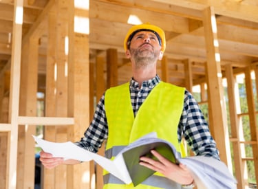 Manlig byggprojektledare tittar upp mot en byggnad.