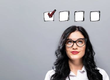 Kvinna funderar vilka krav som ska uppfyllas som illustreras genom ett antal checkboxar ovanför för hennes huvud. .