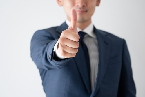 Man i kostym visar tumme upp.