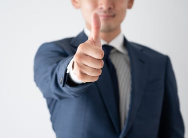 Man i kostym visar tumme upp.