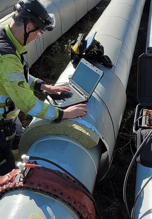 En man använder Long Range Screening, även känt som LRUT, för upphöjda och synliga rör. Provningen är en icke-förstörande metod för att snabbt hitta korrosionsskador i olika slags rörledningar utan att ta rören ur drift..