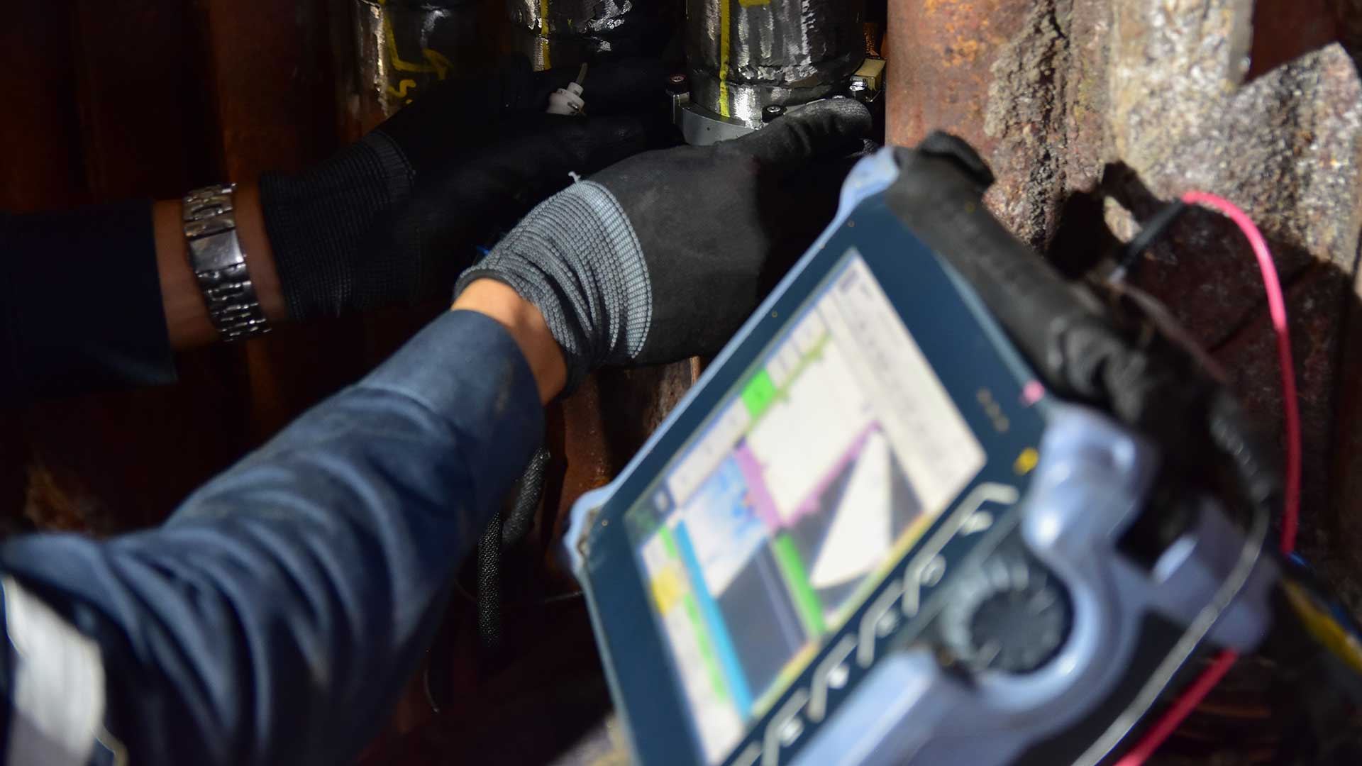 Person som utför ultraljudsundersökning på metallrör med specialutrustning.