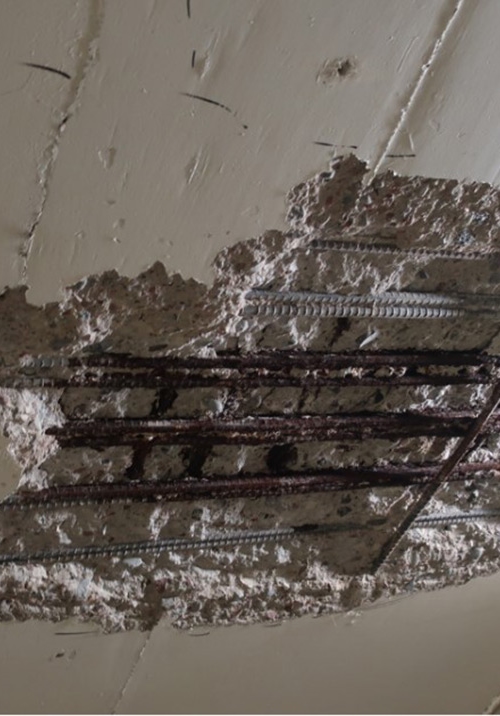 Betongen i ett tak har skadats och blottlagt ett stort hål där även armeringen blivit synlig.