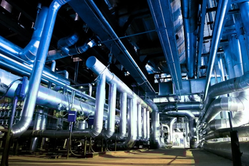 Ett rum fullt med olika slags rörledningar i en industri.