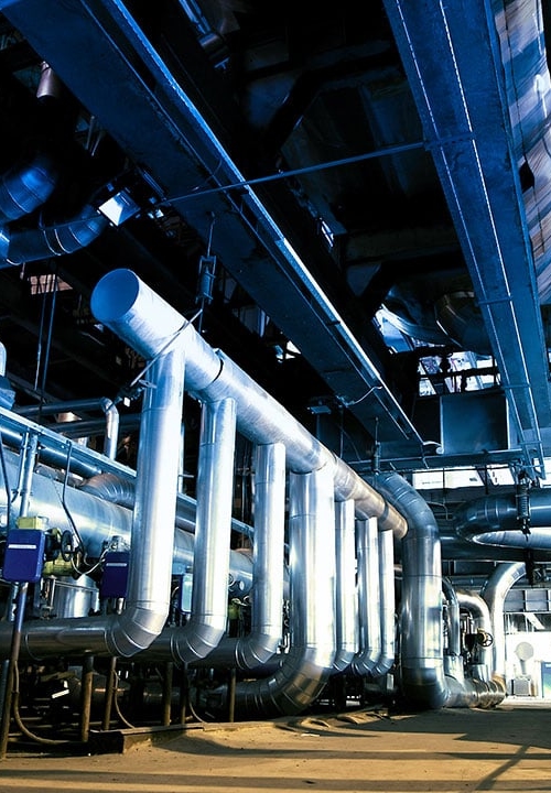 Ett rum fullt med olika slags rörledningar i en industri.