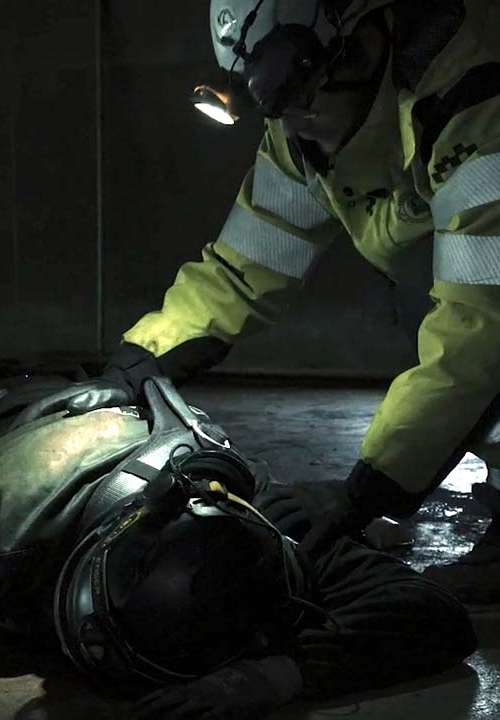 En medvetslös person ligger i mörket på marken , en kollega böjer sig över personen.