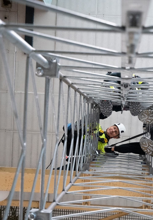 Män med skydds- och fallskyddsutrustninghar klättrat upp i en mast och tittar ner.