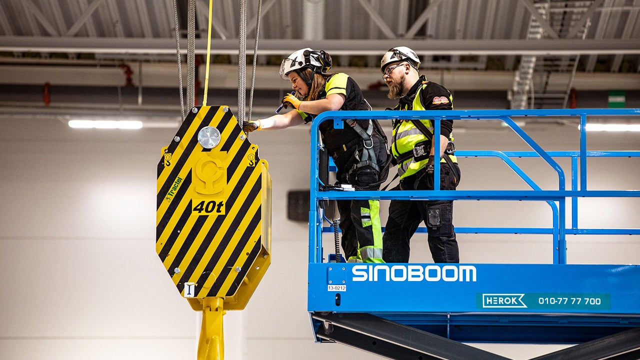 Två personer utför en krankontroll från en mobil arbetsplattform.