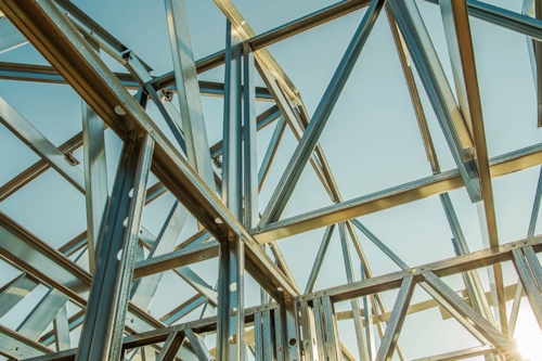 Solen reflekterar mot blänkande stålskelett med blå himmel i bakgrunden.