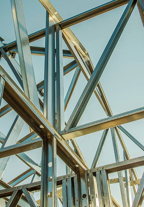 Solen reflekterar mot blänkande stålskelett med blå himmel i bakgrunden.