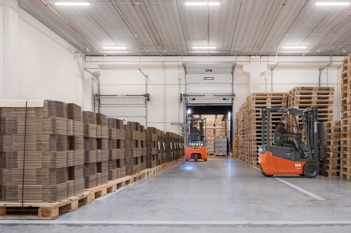 Två truckförare arbetar i ett lager och lastar en lastbil.