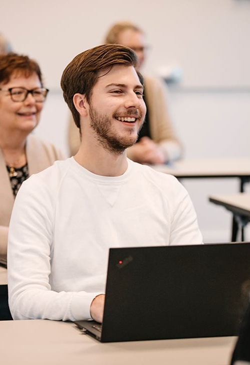 Kursdeltagare sitter i ett klassrum med sin dator framför sig.