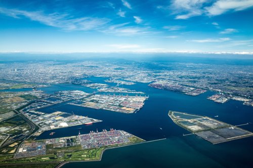 Aerial view of Yokohama, Japan, showcasing the bustling port, industrial areas, and cityscape under a clear blue sky