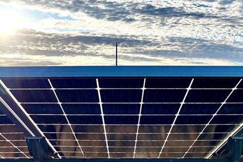 Solar panels on a rooftop under a bright sky with scattered clouds
