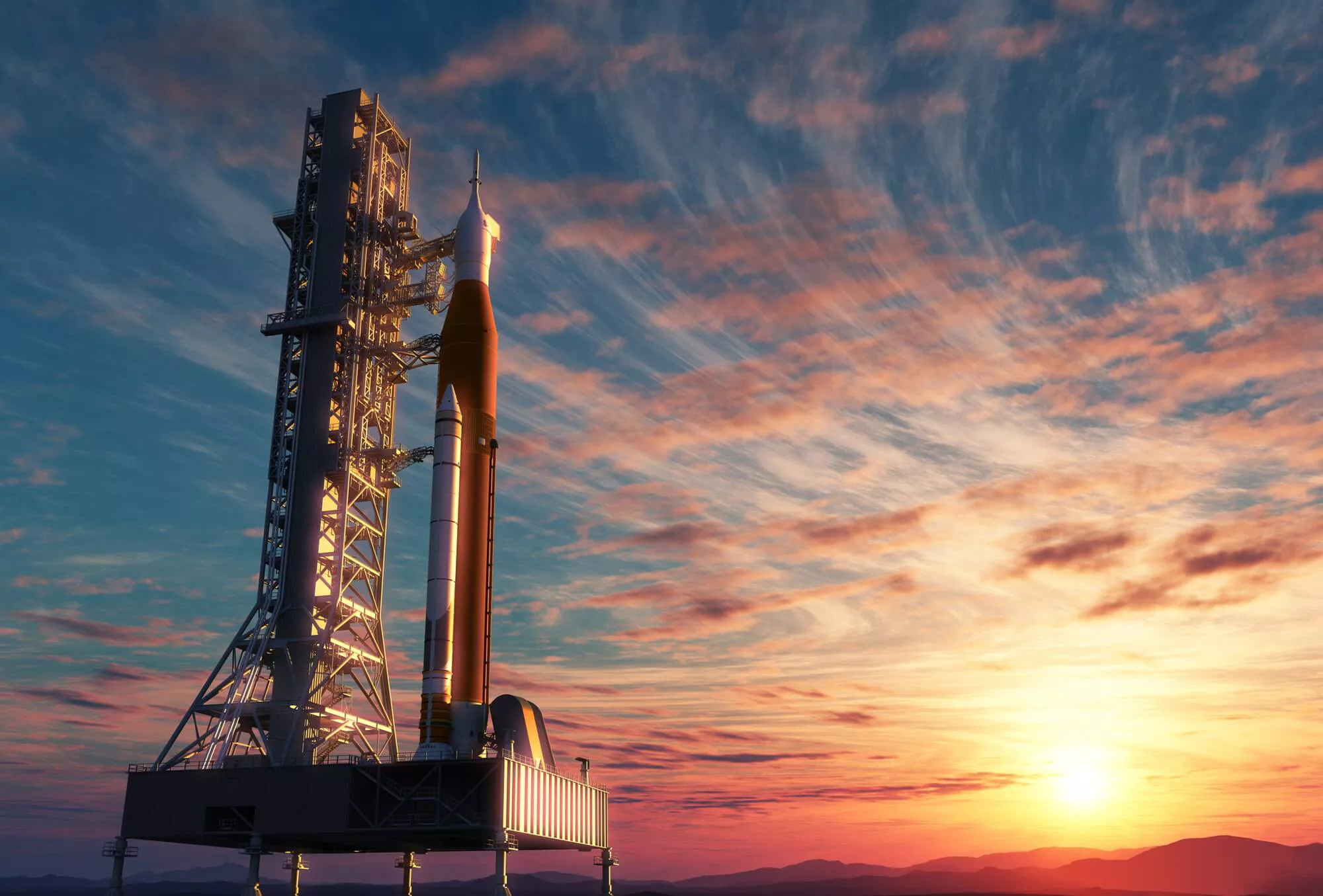 A rocket on a launchpad at sunset with colorful clouds in the sky.