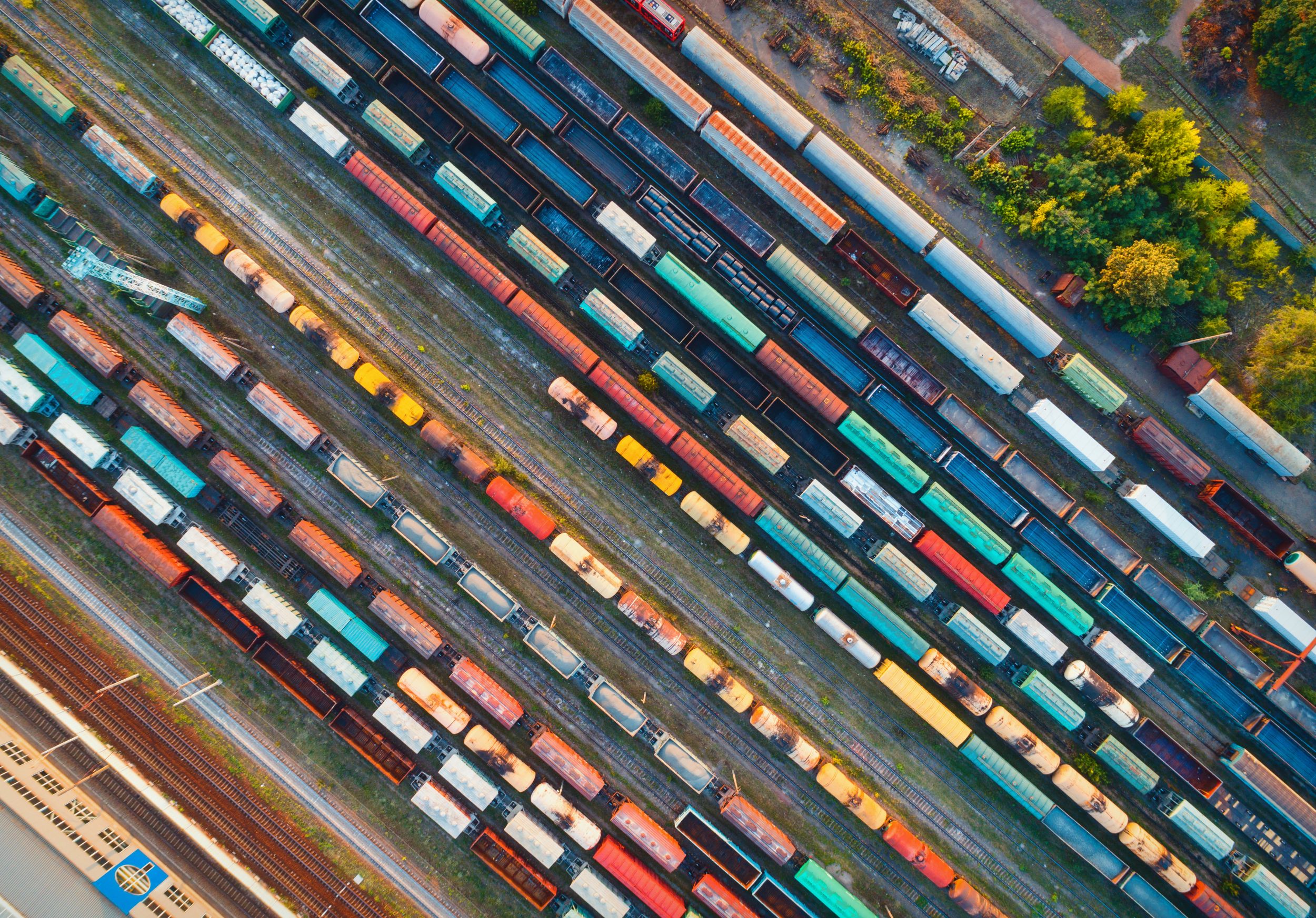 Aerial view of a रेल yard with rows of colorful freight train cars on parallel tracks.
